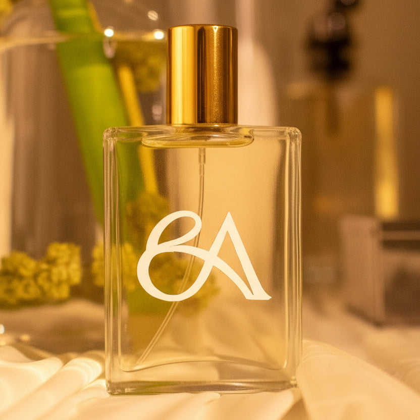 Clear perfume bottle with gold cap and 'BA' logo on a blurred background